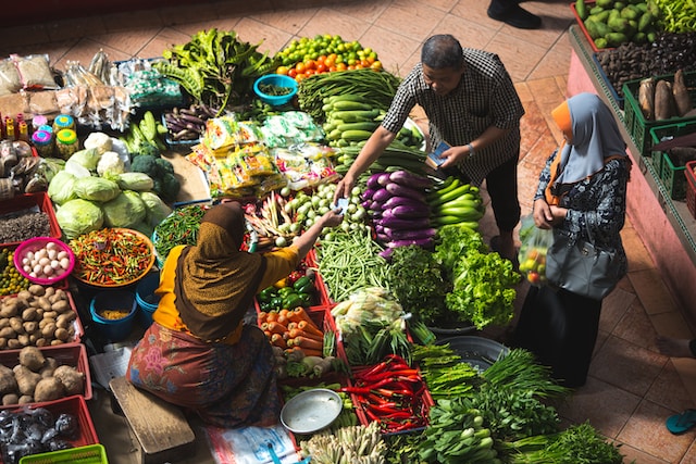 People exchanging money for produce in a market, food systems