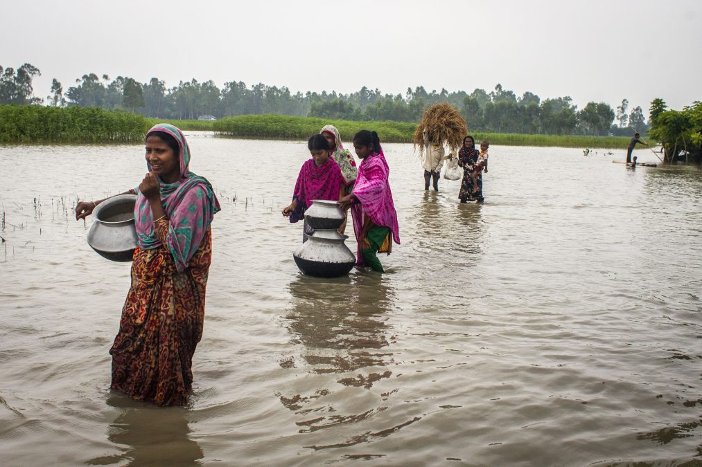Flood victims head off to fetch drinking water using vases at Shakhahati village in Kurigram district, Bangladesh.