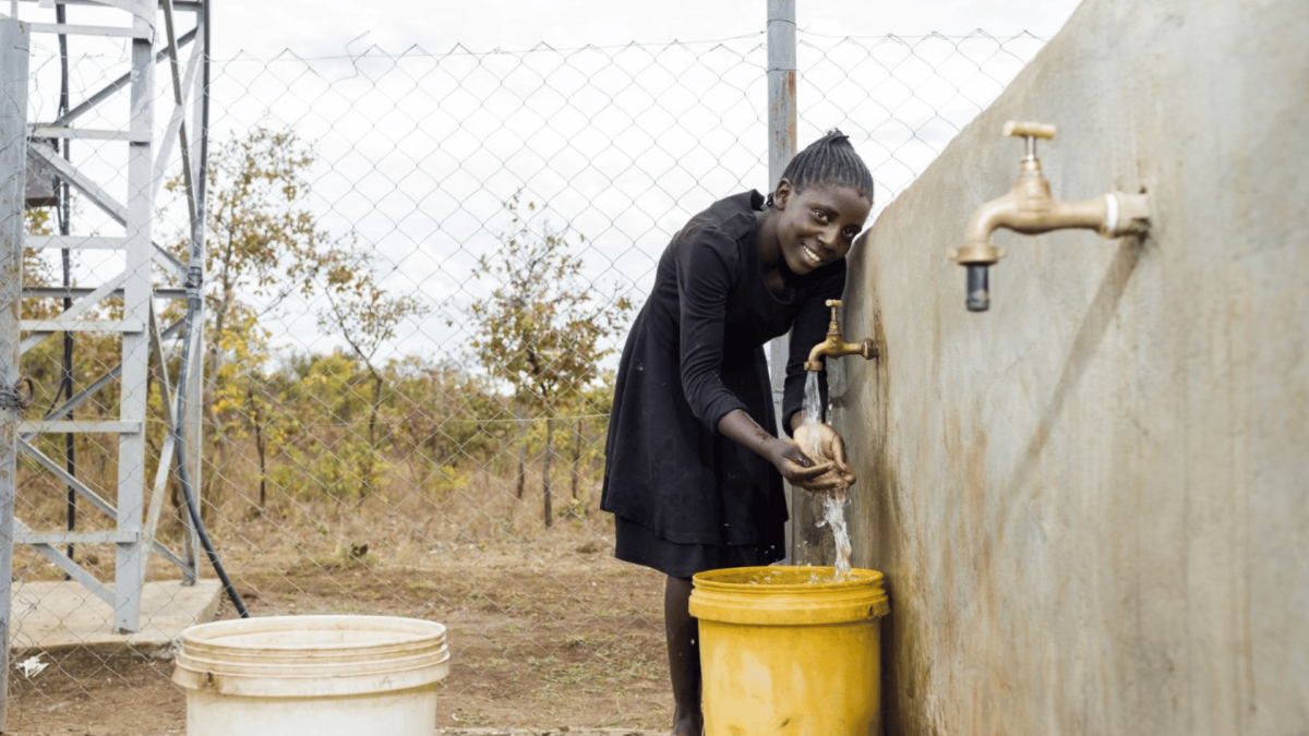 Chanda, from Zambia, collects water at a solar-powered borehole which has been life-changing for her community.